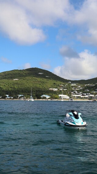 A jet ski on calm water with a backdrop of a coastal town and a hill. 4