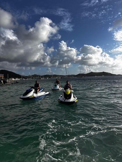 Three people jet-skiing on a body of water with a mountainous landscape in the background. 1