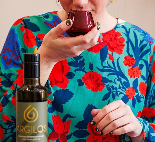 A person holding a bottle of Argilos wine and a glass. 1