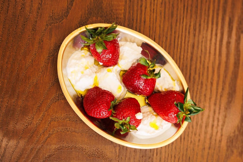 A bowl of strawberries and cream on a wooden table. 3