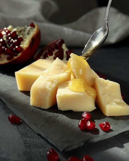 A close-up of cheese cubes with pomegranate seeds and a spoon. 4