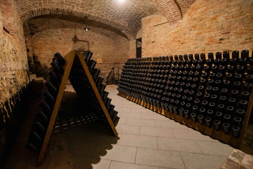 A wine cellar with rows of wine bottles on racks and a wooden rack with more bottles. 4