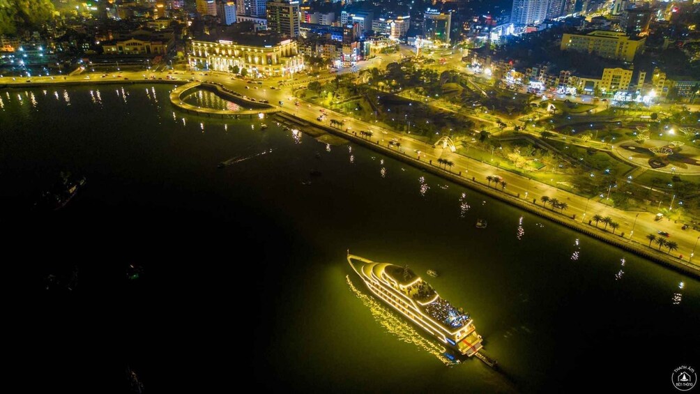 A nighttime cityscape with a river, a bridge, and a lit-up boat. 1
