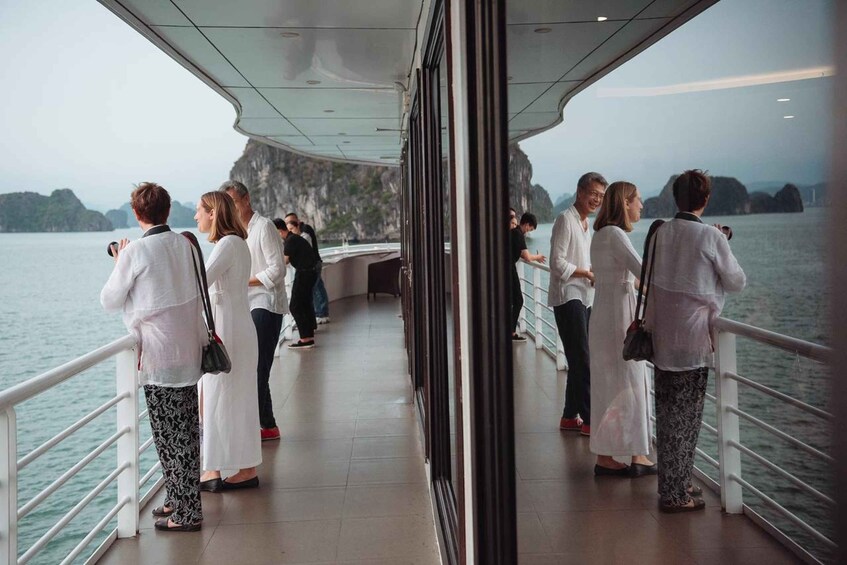 People standing on a boat deck, looking out at a body of water with cliffs in the distance. 5