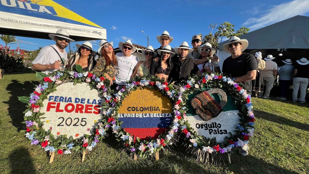 A group of people holding floral wreaths with text and a Colombian flag emblem. 1