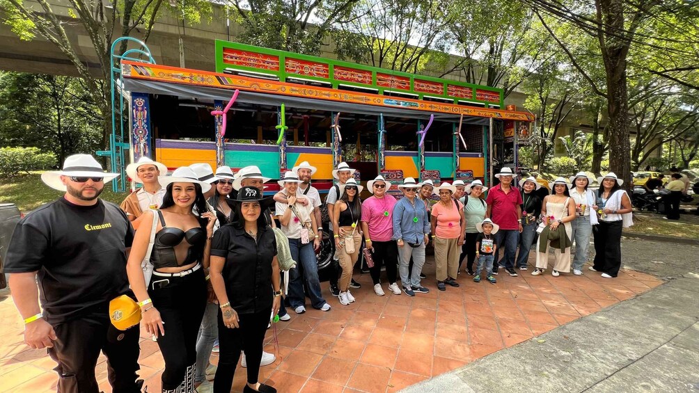 A group of people standing in front of a colorful bus with a green and orange design, under a bridge. 2