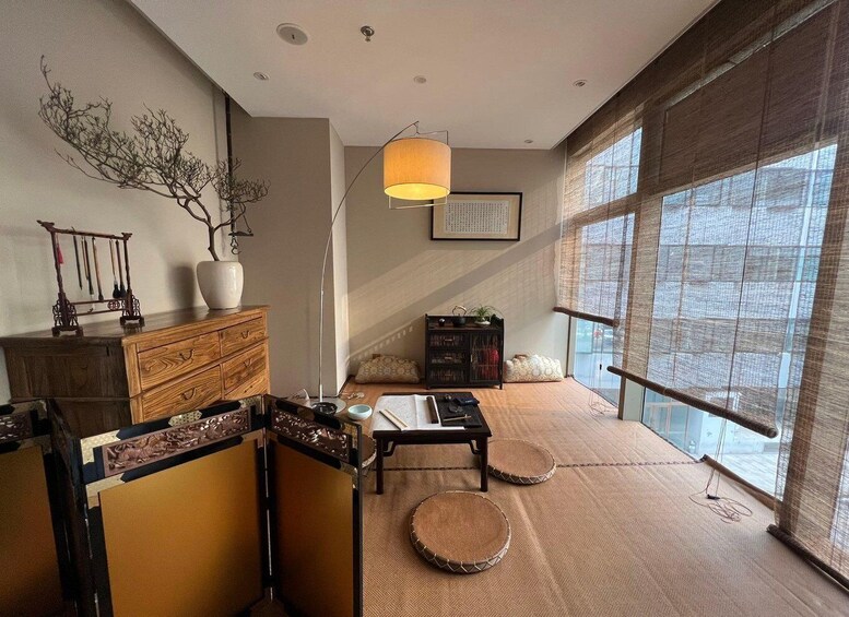 A traditional Japanese room with tatami flooring, a low wooden table, a hanging lamp, and a large window with a view. 1