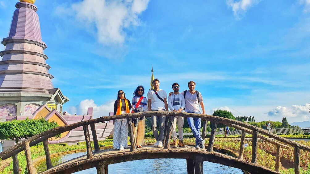 A group of people standing on a wooden bridge with a pagoda in the background. 3