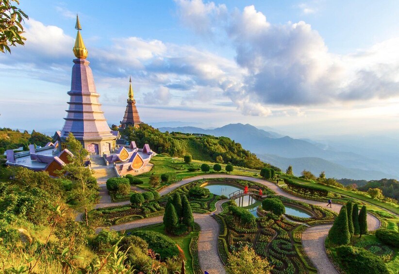 A temple complex with two spires, surrounded by terraced gardens and a mountainous backdrop. 2