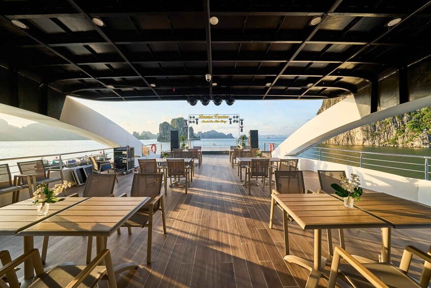 An outdoor dining area with tables and chairs, overlooking a body of water and a distant island. 5