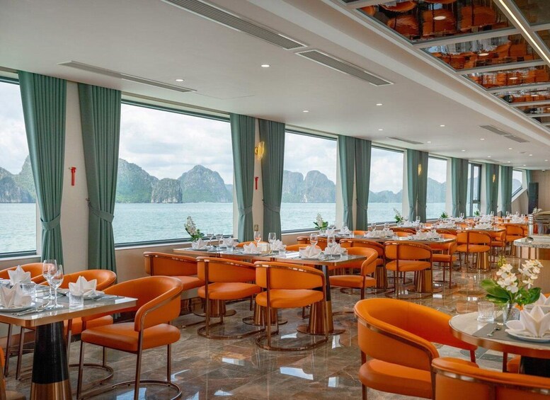 A restaurant with orange chairs and tables, large windows with a view of the sea and mountains. 4