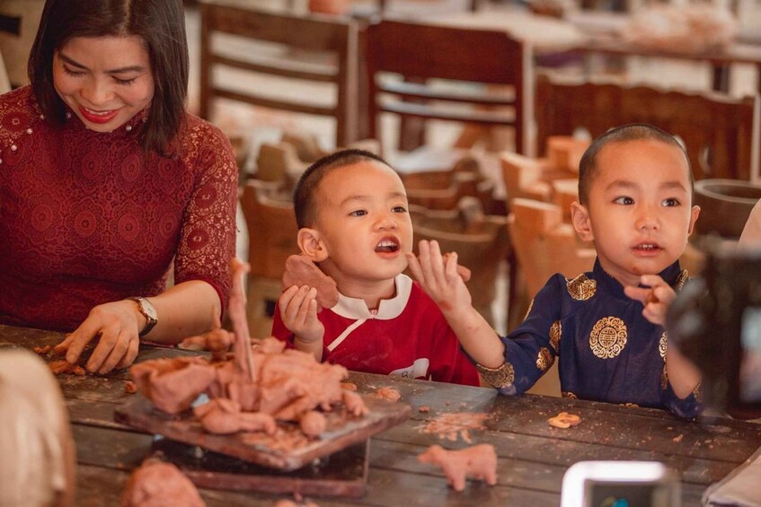 A woman and two children at a table with food remnants, suggesting a meal or cooking activity. 2