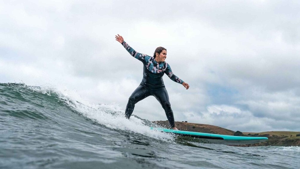 A person surfing on a wave with a coastal landscape in the background. 1
