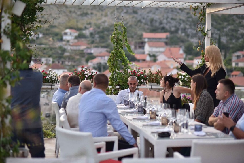 An outdoor dining area with tables set for a meal, surrounded by greenery and overlooking a hillside. 2