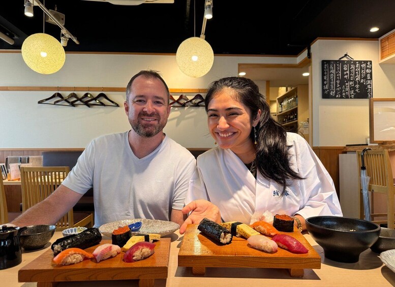 Two people in a restaurant with sushi on the counter. 2