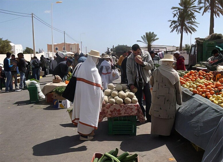 A bustling outdoor market with people shopping and vendors selling fruits and vegetables. 1