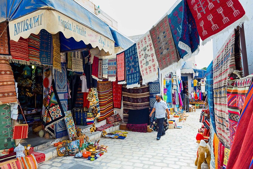 A market with colorful textiles and rugs displayed outside shops. 4