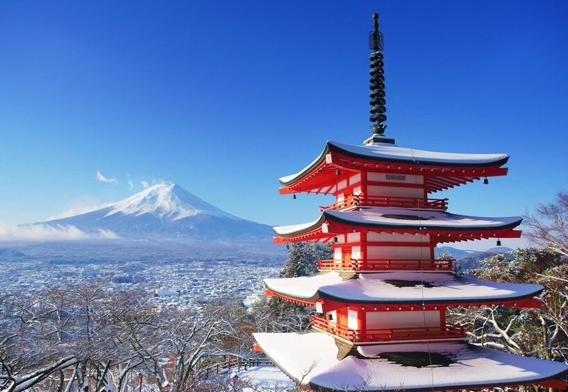 A snow-covered pagoda with Mount Fuji in the background. 4