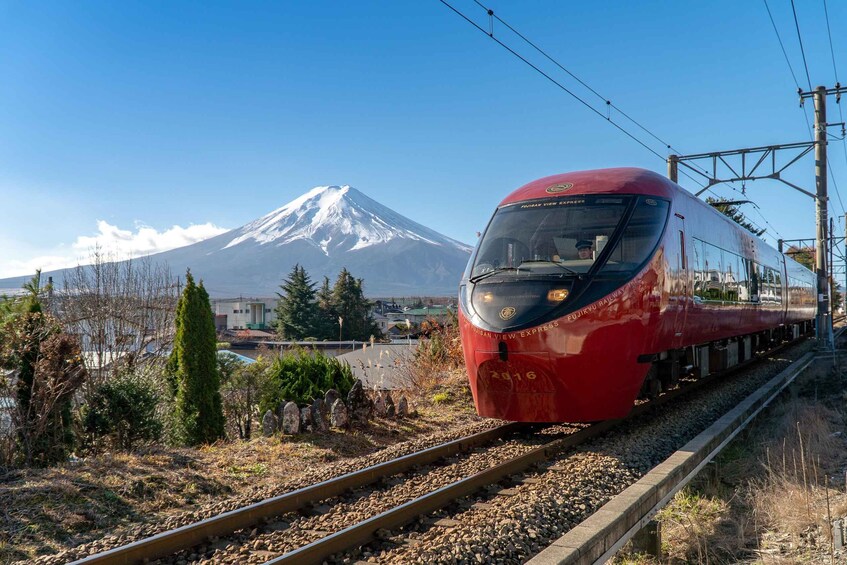 A red train on tracks with a snow-capped mountain in the background. 2