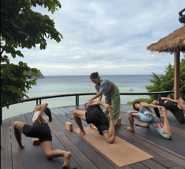 A yoga class on a wooden deck overlooking the ocean. 3