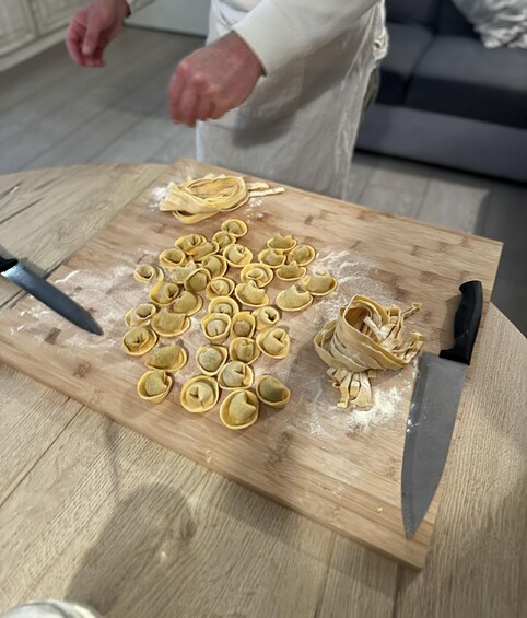 A person preparing ravioli on a wooden cutting board with flour, surrounded by a kitchen setting. 1