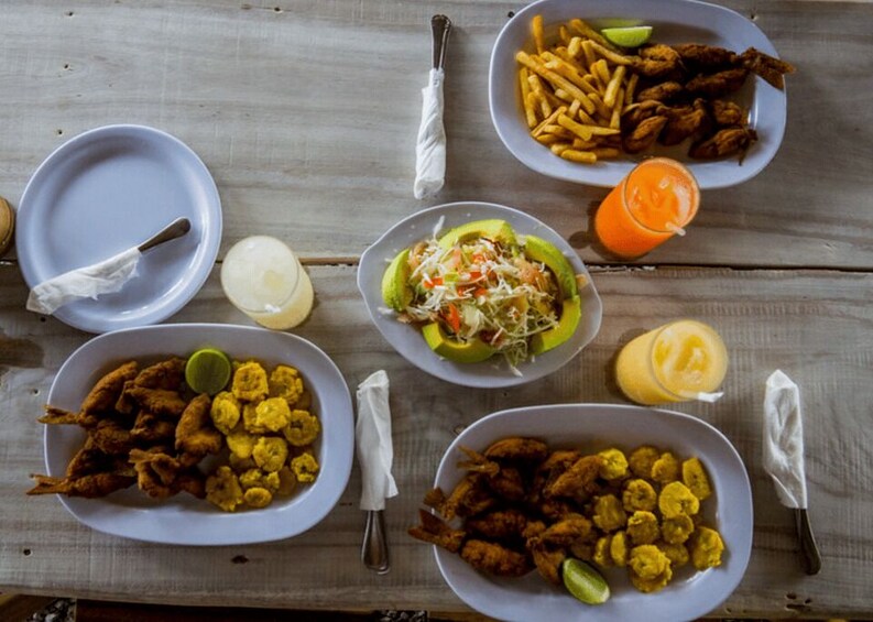 A wooden table with various dishes including fried items, a salad, and a drink. 3