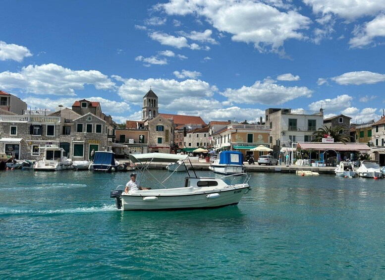 A coastal town with historic buildings, a church tower, and boats docked in the harbor. 4