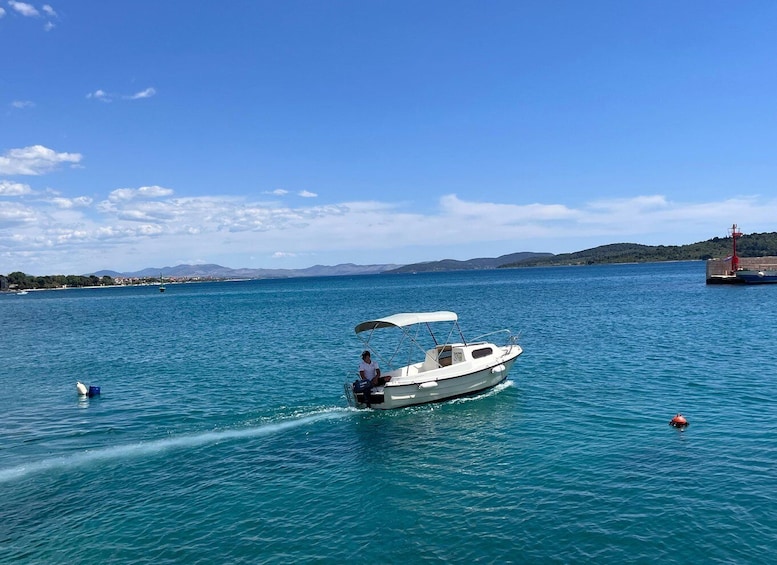 A small motorboat with a canopy on the water, a lighthouse in the background, and a calm sea. 3