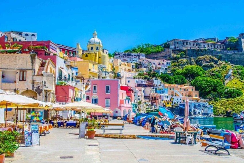 A coastal town with colorful buildings, a prominent yellow church with a dome, and a waterfront with boats. 2