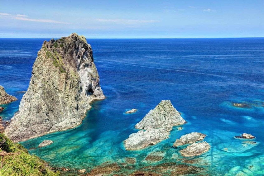 A rugged coastline with a prominent rock formation and clear blue waters. 5