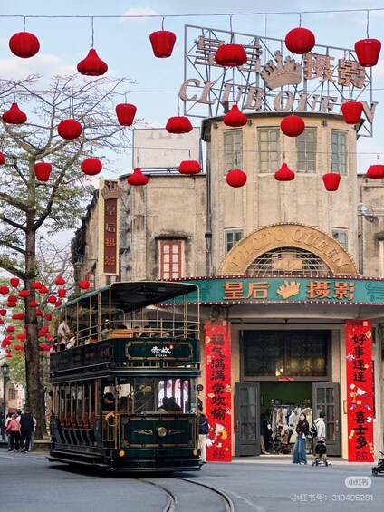 A double-decker tram in front of a building with red lanterns and signage. 4