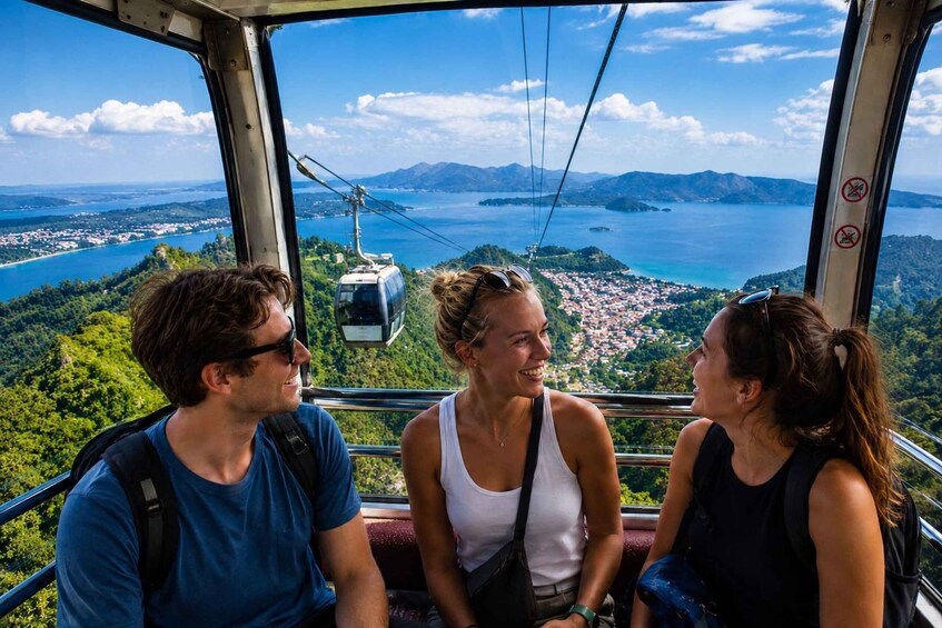 Three people on a cable car with a scenic view of a lake and mountains. 1