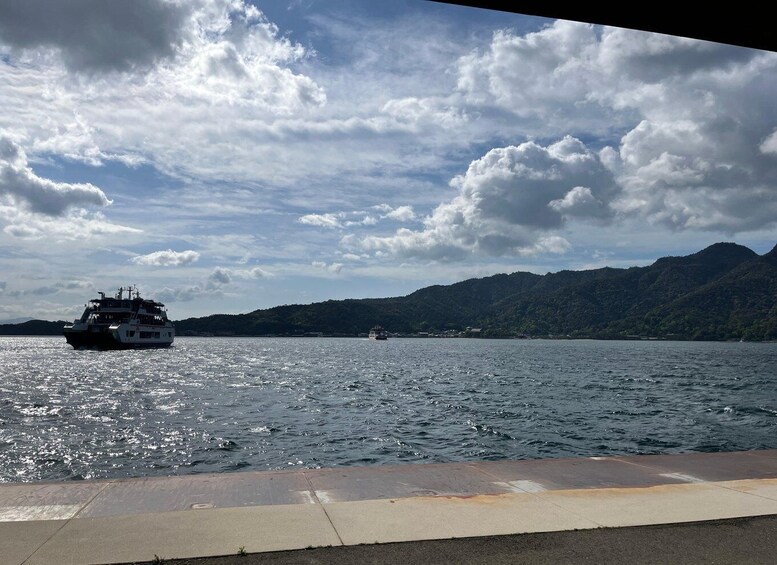 A ferry on a body of water with mountains in the background. 5