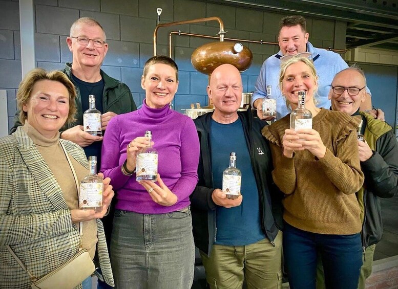 A group of people holding bottles in a room with industrial equipment. 3