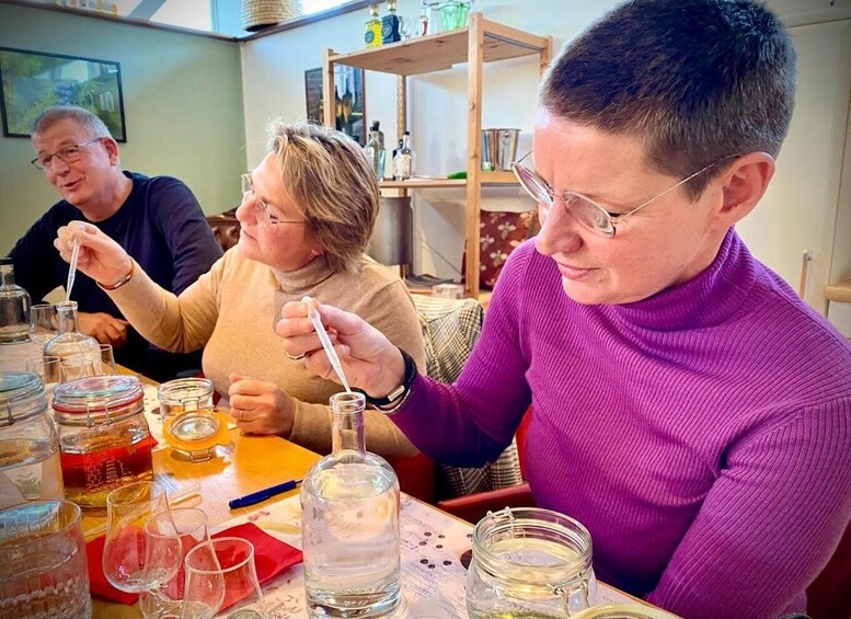Three people engaged in a scientific activity, possibly a chemistry experiment, with various glassware and liquids on a table. 2