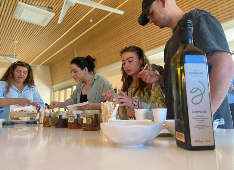 People tasting food at a tasting event with various dishes and a bottle of wine on the table. 3