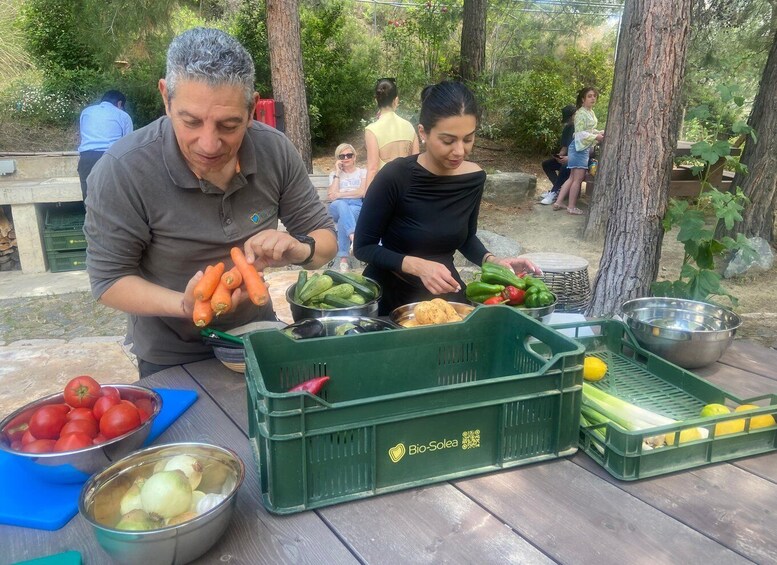 People preparing food outdoors with vegetables and fruits on a table. 2
