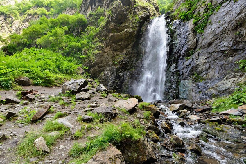 A waterfall cascading down a rocky cliff surrounded by lush greenery. 5