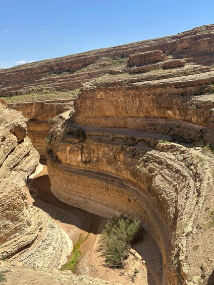 A canyon with layered rock formations and sparse vegetation. 2