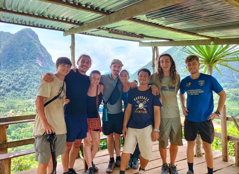 A group of people posing on a wooden deck with a mountainous landscape in the background. 3