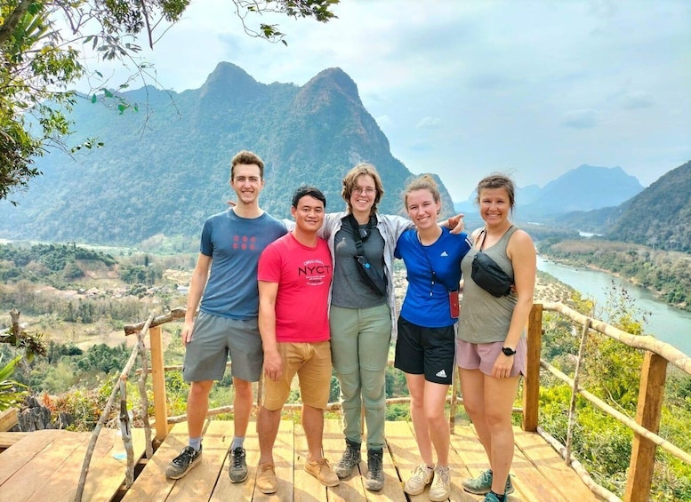 A group of people standing on a wooden platform with a mountainous landscape in the background. 4