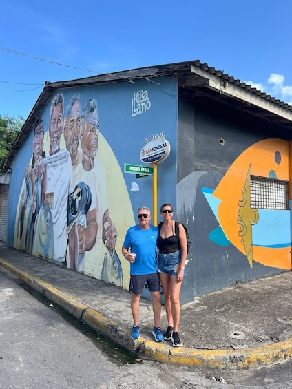 A mural on a building with a man and a woman standing in front. 1