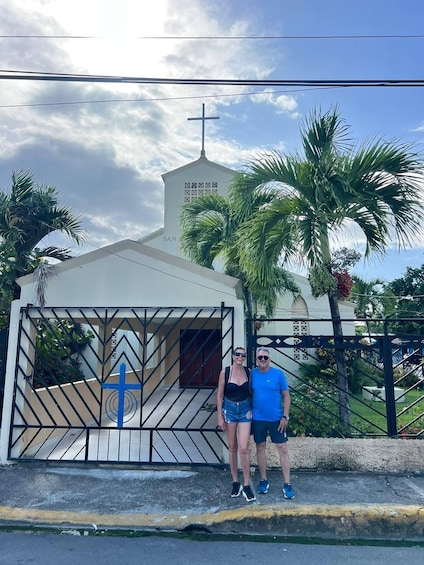 A church with a cross, a gate, and palm trees. 3