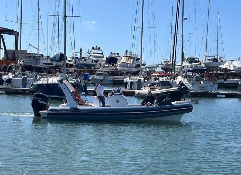 A marina with multiple sailboats docked and a motorboat with people on board. 1