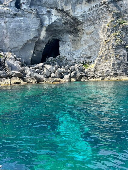 A rocky coastline with a cave entrance and clear turquoise water. 2