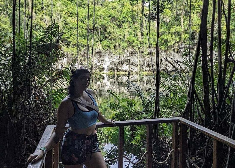 A person standing on a wooden deck overlooking a forested area with a body of water. 5