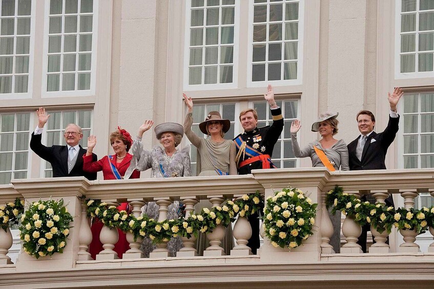 A group of people on a balcony with flowers and a building in the background. 1