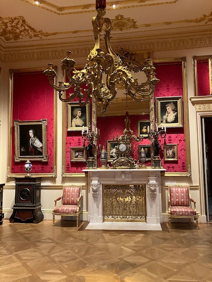 An opulent room with a grand chandelier, red wallpaper, and ornate furniture. 3