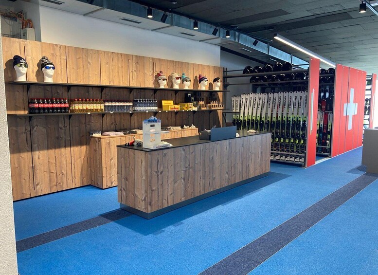 A ski shop interior with wooden counters, ski equipment, and a blue carpeted floor. 1