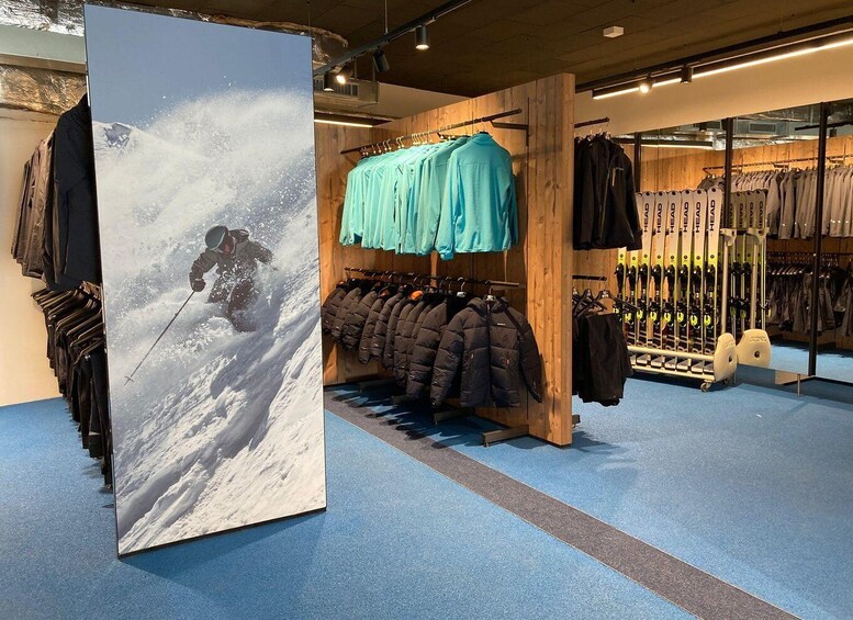 A ski store with racks of jackets and a large poster of a skier on a snowy mountain. 2